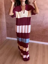 Vestido largo de tejido de punto con diseño a rayas horizontales en tonos bordó, crema, rosa y celeste. Presenta cuello polo con escote en V y mangas cortas con textura acanalada.