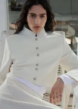 Chaqueta corta de diseño recto con cuello mao y cierre frontal de botones con efecto joya. Posee mangas largas y forro interior.