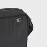 Bolso tipo morral Adidas de diseño minimalista, color negro, confeccionado en nylon reciclado. Presenta el logotipo del Trifolio en relieve en el frente, cierre de cremallera y correa ajustable para llevar al hombro o cruzado.