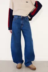 Jean de tiro alto con corte barrel leg, confeccionado en denim azul clásico. Presenta un diseño de pierna ancha y holgada, con cierre frontal de botón y cremallera, y bolsillos laterales y traseros.