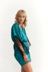 Vestido corto celeste de satén con escote en V, mangas cortas con flecos negros y drapeado en la falda.