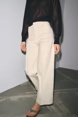 Jeans de tiro alto, pierna ancha y largo al tobillo, en denim celeste claro con efecto lavado. Presenta costura marcada en el centro de cada pierna y cierre frontal con cremallera y botón.