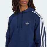 Canguro con capucha Adidas de color azul marino, con las clásicas tres tiras blancas en las mangas, bolsillo tipo canguro y el logo del Trifolio bordado en el pecho.