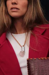 Collar con tiento de cuero marrón y dije con forma irregular, compuesto por un cilindro de metal dorado, una piedra amatista y una piedra de cuarzo transparente.