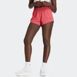 Short de running New Balance RC, color coral/rosado, con cintura elástica y cordón ajustable. Presenta un calzoncillo interior integrado y logo reflectante en el muslo.