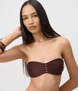 Top de bikini bandeau color marrón en tejido de microfibra texturizado, sin breteles y con detalle calado central de tiras horizontales.