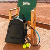 Mochila deportiva negra de diseño minimalista, con múltiples compartimentos, incluyendo espacio térmico para raquetas, bolsillo inferior ventilado para calzado y compartimento interno para laptop.