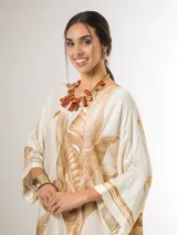 Vestido maxi túnica de corte oversized, color beige y blanco con estampa de hojas de palmera en tonos camel, mangas murciélago y bolsillos laterales.