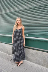 Vestido largo de crepe con estampado de lunares negros sobre fondo blanco. Presenta un diseño de corte holgado con breteles finos y escote redondeado.