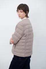 Campera acolchada tipo puffer en color beige, con diseño sin cuello y cierre frontal con botones a presión.