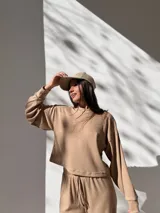 Buzo de tejido waffle color beige, con cuello redondo, mangas largas con puños y corte cropped.