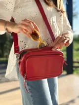 Bandolera roja de cuero con forro de tela, con bolsillo interior y exterior.