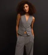 Pantalón de vestir gris de corte recto, con bolsillos laterales y traseros. Se ajusta a la cintura con cierre asimétrico de botones.