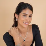 Collar con cadena de eslabones trenzados en plata con detalles en oro, que sostiene un dije circular con piedra ónix negra central y borde en oro.