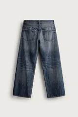 Jeans de denim de algodón en color azul con efecto desgastado, tiro medio y corte recto de ajuste holgado (loose fit). Cuenta con diseño clásico de cinco bolsillos y cierre frontal con cremallera y botón.