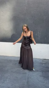 Vestido largo de diseño combinado, con cuerpo superior ajustado de efecto cuero en color chocolate y falda inferior fluida de gasa semitransparente. Presenta escote recto con breteles finos.