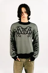 Sweater reversible de tejido de punto con diseño gráfico estilo tribal. Un lado presenta base negra con detalles en gris, mientras que el otro lado presenta base gris con detalles en negro. Posee cuello redondo, mangas largas y puños acanalados.
