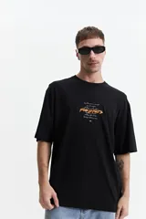 Remera negra de manga corta con corte oversize y cuello redondo. Presenta un estampado pequeño en la espalda con texto en naranja y blanco que dice "Free Spirits Freedom & Waves All Day / Every Day".