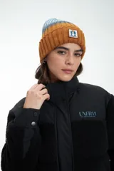 Campera negra de estilo urbano, confeccionada en una combinación de tela técnica y textura tipo corderito (fleece). Presenta cierre frontal con solapa y botones a presión, cuello alto y logo estampado en el pecho.