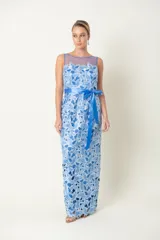 Vestido largo de fiesta celeste con encaje floral, hombros descubiertos con tul y lazo azul en la cintura.