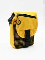 Morral amarillo de lona con detalles en negro, solapa frontal con cierre de hebilla plástica, bolsillo con cierre y detalles de red lateral.