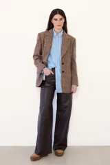 Blazer de corte sastrero confeccionado en paño con estampado de cuadros escoceses. Presenta parches decorativos en las mangas y espalda, bordados en el bolsillo y manga, y cierre frontal con botones.
