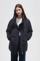 Campera puffer negra de corte holgado, con cuello alto, cierre frontal oculto y bolsillos laterales.