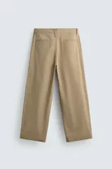 Pantalón chino de corte wide fit confeccionado en tejido de algodón. Presenta pliegues frontales, bolsillos laterales y bolsillos traseros de vivo, con cierre frontal de cremallera y botón.
