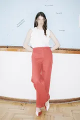 Pantalón de lino rojo coral, de corte ancho y tiro alto, con bolsillos laterales y cierre frontal con botón y cremallera.