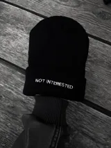 Gorro de lana negro con la frase "Not Interested" bordada en blanco.