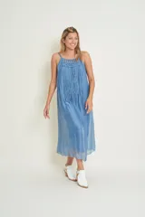 Vestido midi azul de seda natural con breteles finos y escote redondo. Presenta detalle de flecos largos en el frente.