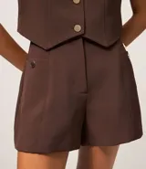 Short sastre de cintura alta con estructura definida, bolsillos laterales decorados con tachuelas metalizadas y recortes delanteros con costura aparente.