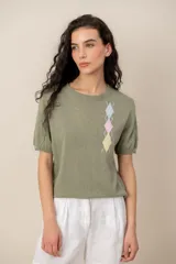 Sweater Dalia de punto fino color verde militar, manga corta abullonada y cuello redondo. Presenta un diseño de rombos geométricos multicolores en el lateral izquierdo del pecho.