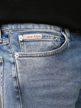 Pantalón de jean celeste, corte slim tapered, con bragueta con cremallera y diseño de cinco bolsillos. Calvin Klein.