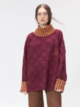 Pullover de punto jacquard con diseño de cuadros en relieve, cuello alto y mangas largas. Presenta detalles de pespuntes en color rojo en el cuello y los puños, aberturas laterales y logo bordado en el pecho.