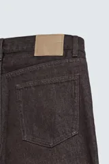 Jeans flare fit de denim negro, con tiro medio, corte ajustado en la parte superior y ligeramente acampanado desde la rodilla. Diseño de cinco bolsillos y cierre frontal con botones.