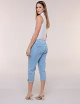 Capri blanco de corte ajustado, con tiro alto y pretina ancha elastizada tipo faja. Presenta bolsillos falsos al frente con remaches, piernas entalladas con pequeñas aberturas en los laterales y ruedo desflecado.