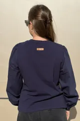 Remera de algodón color azul marino, con cuello redondo fruncido y mangas largas abullonadas con puños elásticos.