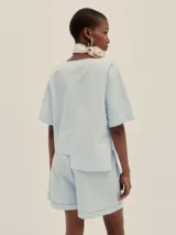 Shorts celestes a rayas verticales, de tiro alto y corte holgado, con pinzas en el frente y detalle de Polonio en cobre.