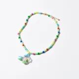 Collar corto con cuentas de colores y dije de pez de vidrio transparente con detalles en azul, naranja y verde.