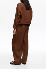 Pantalón de lino color marrón de corte recto y tiro medio, con bolsillos laterales y pinzas delanteras.