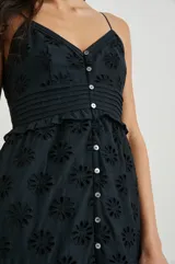 Vestido largo negro con breteles finos, escote en V y botones frontales. Presenta bordados florales calados y volados en la falda.