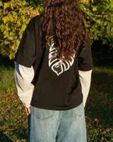 Remera de diseño superpuesto con cuerpo de algodón negro y mangas largas tejidas en color blanco. Presenta un corte boxy relajado y logo de la marca estampado en el pecho.