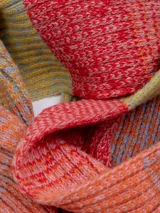 Bufanda tejida de punto con diseño jacquard multicolor en tonos naranja y rojo.