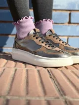 Zapatillas deportivas de cuero color peltre, con cordones negros y suela de goma blanca.