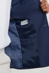 Saco azul de lino, de corte clásico, con solapa de muesca, cierre de dos botones, bolsillos frontales con solapa y aberturas traseras.