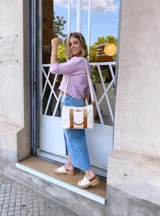 Bolso tipo tote de lona color crudo con detalles en cuero color marrón. Tiene doble asa corta de mano y correa larga de hombro.