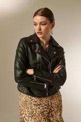 Campera de estilo biker confeccionada en eco-cuero negro, con solapas, cierre frontal, bolsillos con cremallera y detalles acolchados en los hombros.