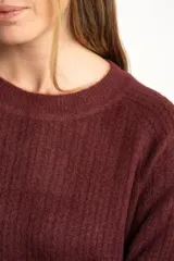Sweater de punto con textura acanalada, cuello redondo y mangas largas. Presenta un diseño de calce holgado con ruedo redondeado y aberturas laterales.