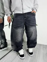 Jeans baggy color negro con efecto acid wash, corte holgado, diseño de paneles con costuras pespunteadas y detalles de texto estampado a lo largo de las piernas.